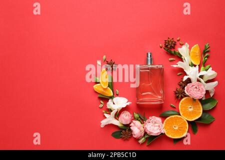 Composition de la couche plate avec bouteille de parfum et agrumes frais sur fond rouge. Espace pour le texte Banque D'Images