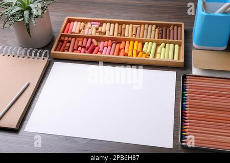 Feuille de papier vierge, pastels à la craie colorés et crayons à dessin sur table en bois. Le lieu de travail de l'artiste moderne Banque D'Images