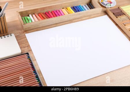 Papier vierge, pastels doux et crayons à dessin sur une table en bois sur le lieu de travail de l'artiste. Espace de conception Banque D'Images