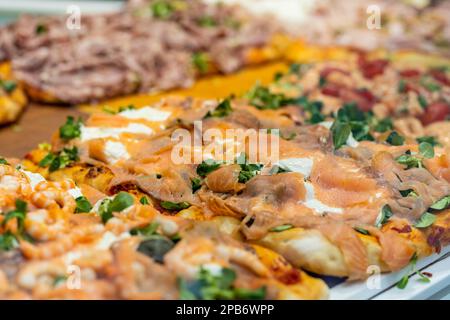 Morceaux carrés de pizza exposés sur le comptoir de la petite pizzeria italienne dans la ville de Bergame, Italie. Banque D'Images