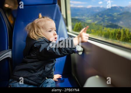 Enfant voyageant en train. Petit enfant assis près de la fenêtre en train express pendant les vacances en famille. Enfant dans une voiture de chemin de fer. En vacances avec Banque D'Images