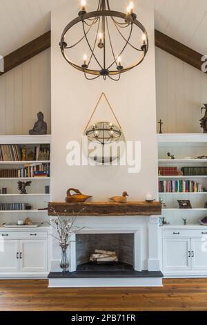 Foyer décoratif peint en blanc entre les bibliothèques et les planchers de bois de pin rouge dans la chambre principale à l'intérieur de la maison hybride en bois de construction. Banque D'Images