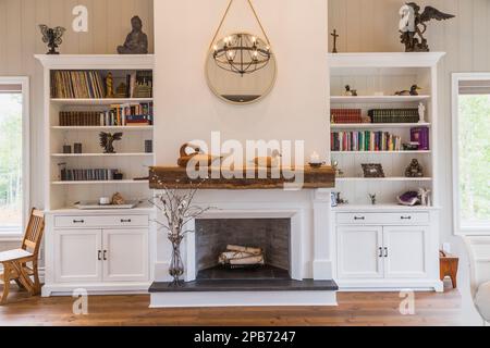 Foyer décoratif peint en blanc entre les bibliothèques et les planchers de bois de pin rouge dans la chambre principale à l'intérieur de la maison hybride en bois de construction. Banque D'Images