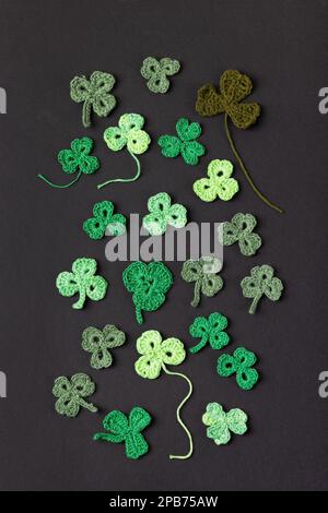 Bordure latérale de Saint-Patrick en tricot de shampoings verts sur fond noir. Affiche des fêtes et feuille de trèfle tricotée. Espace de copie, plan de travail Banque D'Images