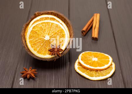 Anis étoilé et tranches d'orange séchées en noix de coco. Bâtons de cannelle sur la table. Vue de dessus. Arrière-plan en bois sombre. Banque D'Images