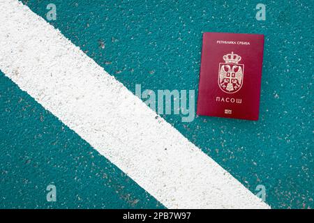 Passeport national serbe à côté d'une ligne blanche au sol. Symbolique, frontière Banque D'Images