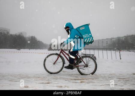 Moscou, Russie. 12th mars 2023. Un messager du service de livraison Yandex Lavka roule à vélo pour livrer une commande à un client dans une lourde chute de neige dans un quartier résidentiel de Moscou, en Russie Banque D'Images