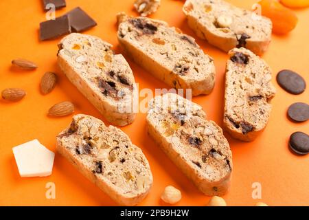 Délicieux biscuits en biscotti, noix et chocolat sur fond orange Banque D'Images