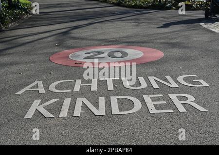 Rue avec le panneau pour la limite de vitesse 20 kilomètres par heure et l'inscription en langue allemande qui dit attention aux enfants. Banque D'Images