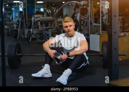 un homme blond fait de l'exercice dans la salle de gym Banque D'Images