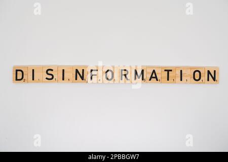 Le titre en bois épelant le mot désinformation isolé sur un fond blanc Banque D'Images