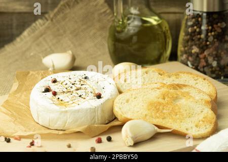 Camembert cuit au four avec épices sur papier de cuisson. Fromage frit maison sur une table rustique. bannière, menu, placer pour le texte, vue de dessus Banque D'Images