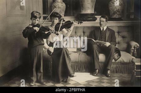 1909 CA, Bruxelles , Belgique : la Reine ELISABETH de Belgique ( née Duchesse de Bavière , 1876 - 1956 ) avec le groupe de la famille royale LÉOPOLD III des Belges SAX COBURG GOTHA ( 1901 - 1983 ) . Dans cette photo Elisabeth donne des leçons de violon à son fils, le futur roi LÉOPOLD III des Belges SAX COBURG GOTHA ( 1901 - 1983 ) Quand était un jeune garçon et duc de Brabant - Maison de BRABANT - BRABANTE - Maria - SAVOIE - royalties - nobili - Nobiltà - BELGIO - BELGIQUE - portrait - ritratto - BELLE EPOQUE - collier - perles - collana di perle - bijoux - gioiello - gioielli - bijoux - bijoux - pizzo - l Banque D'Images