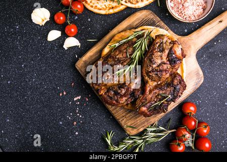 Steaks. Steak de viande grillé en tranches New York ou Ribeye avec épices romarin et poivre sur tableau noir. Vue de dessus. Banque D'Images
