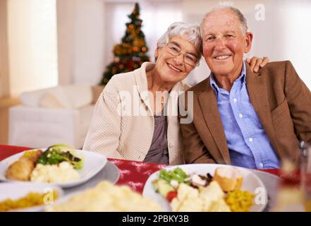Une bonne cuisine et une entreprise encore meilleure rendent les fêtes de Noël plus joyeuses. Portrait d'un couple senior affectueux le jour de Noël. Banque D'Images