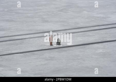 Une paire de pêcheurs entre les lignes électriques sur la mince glace de printemps du réservoir de Voronezh. Chaque année, les amoureux désespérés de la pêche d'hiver prennent la glace du réservoir de Voronezh. Les pêcheurs ne sont pas arrêtés par un dégel ou même par l'arrivée du printemps. L'excitation pousse ces gens sur de la glace mince et parfois floue, ce qui crée des tensions pour les services de service de la ville. Les sauveteurs et la police délèvent les pêcheurs des banquise et les pêchent dans les goulets, tandis que les travailleurs médicaux se battent pour la vie des personnes qui se noient ou qui sont froides. (Photo de Mihail Tokmakov/SOPA Images/Sipa USA) Banque D'Images