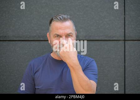 Homme barbu d'âge moyen tenant sa main sur son visage avec les doigts tordus pendant qu'il regarde la caméra Banque D'Images
