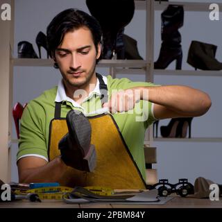 Le jeune cordonnier en atelier la nuit Banque D'Images