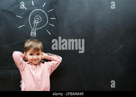 HES a eu beaucoup d'idées. Photo en studio d'un jeune garçon avec une ampoule à dessin de craie au-dessus de sa tête. Banque D'Images