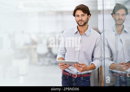 HES un jeune homme d'affaires confiant. Portrait d'un beau jeune homme d'affaires debout dans son bureau. Banque D'Images