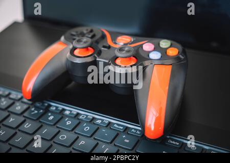le joystick de la console de jeux est noir et rouge et l'ordinateur portable. Le concept de l'industrie du jeu et un passe-temps amusant à la maison. Banque D'Images
