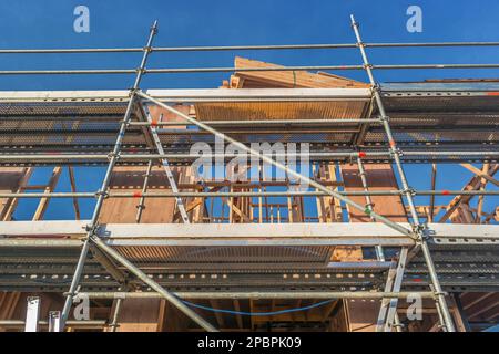 Vue en angle bas d'un bâtiment en bois en construction, entouré d'échafaudages et de poutres apparentes Banque D'Images