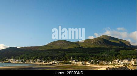 Les montagnes de Mourne ont vue depuis la plage du comté de Newcastle en bas, avec un ciel bleu et des maisons en bord de mer Banque D'Images