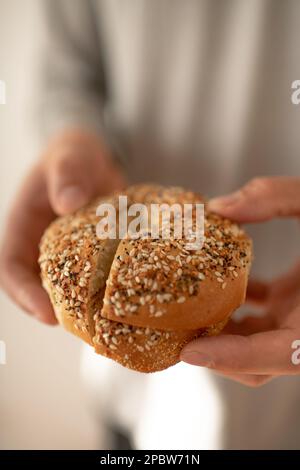 Personne tenant un Bagel tout à manger pour le petit déjeuner Banque D'Images