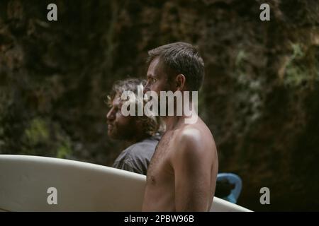 Homme avec une planche de surf va à la tache de surf d'Uluwatu. Banque D'Images
