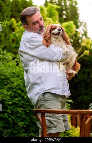 Portrait d'un homme âgé avec son chien dans le jardin. Banque D'Images
