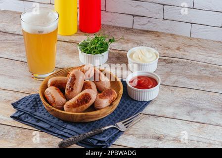 saucisses grillées dans une assiette, sauces et bière à proximité Banque D'Images