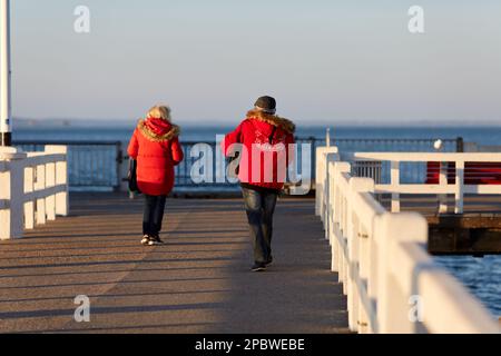 couple senior vêtu de rouge marchant sur la jetée Banque D'Images