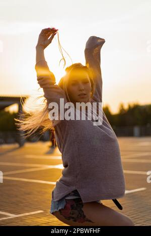 La femme danse au coucher du soleil, en mouvement, cheveux volants. Banque D'Images