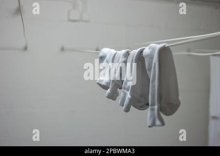 Pyjama blanc ou vêtements et chaussettes courtes accrochées aux lignes de séchage à l'intérieur de la buanderie commune à l'intérieur de l'immeuble d'appartements. Personne. Banque D'Images