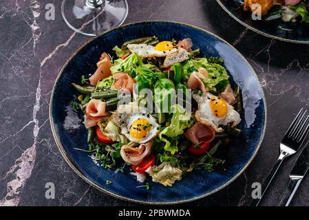 salade avec œufs de caille, bacon, légumes, herbes et sauce Banque D'Images