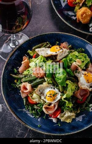 salade avec œufs de caille, bacon, légumes, herbes et sauce Banque D'Images