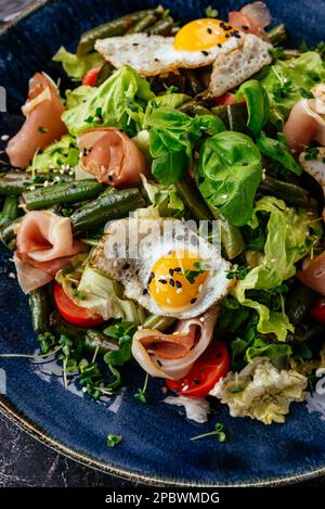 salade avec œufs de caille, bacon, légumes, herbes et sauce Banque D'Images