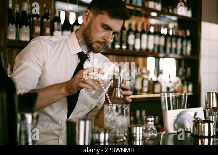 Un jeune barman travaille dans un bar pour faire un cocktail. Banque D'Images