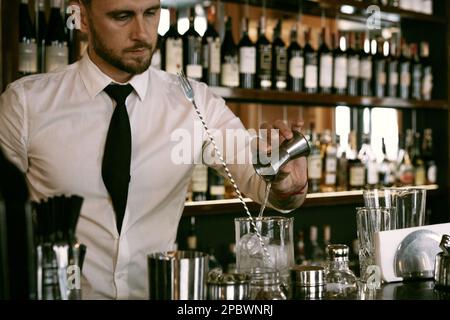 Un jeune barman travaille dans un bar pour faire un cocktail. Banque D'Images