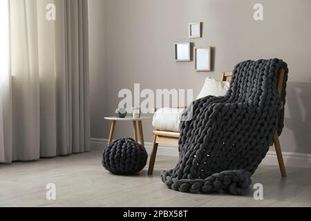 Couverture en grosse maille douce sur le fauteuil dans la chambre. Design intérieur Banque D'Images