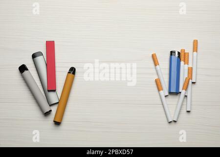 Cigarettes avec briquet et différents dispositifs de vapotage sur fond blanc en bois, plat. Alternative fumeurs Banque D'Images