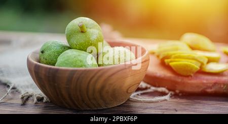 une alimentation saine. Les noix, coupées en tranches, sont dispersées sur une planche à découper. Ancienne table vintage et fruits de noyer entiers non mûrs Banque D'Images