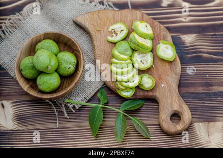 une alimentation saine. Les noix, coupées en tranches, sont dispersées sur une planche à découper. Ancienne table vintage et fruits de noyer entiers non mûrs Banque D'Images