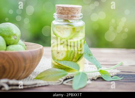Noix vertes non mûres lisses et teinture de noix dans un pot transparent avec couvercle en liège sur une table ancienne. Feuilles sur la branche de l'écrou. Collecter Banque D'Images
