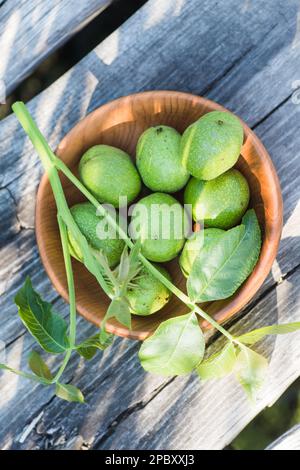 Noix vertes lisses non mûres sur une ancienne table vintage. Feuilles sur la branche de l'écrou. Recueillir les ingrédients pour la teinture des noix. Banque D'Images