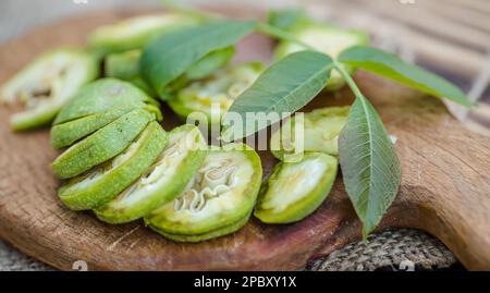 une alimentation saine. Les noix, coupées en tranches, sont dispersées sur une planche à découper. Ancienne table vintage et fruits de noyer entiers non mûrs Banque D'Images