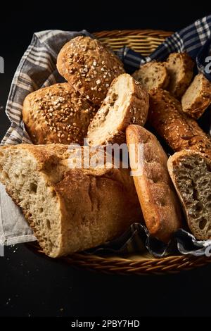 Vue de dessus de délicieux pain fraîchement cuit avec croûte croustillante et mélange de graines coupées et servi sur le panier sur la serviette Banque D'Images