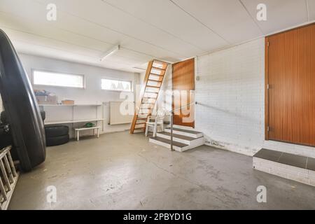 Design intérieur de garage léger avec bateau noir et pneus avec échelle et étagères avec portes en bois et escalier avec murs en briques blanches et béton Banque D'Images