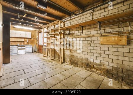 Intérieur d'un vieux garage miteux avec des murs en briques et des étagères près des placards éclairés par des lampes Banque D'Images