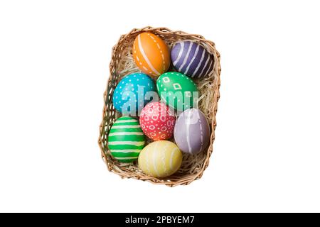 Panier d'œufs de Pâques colorés isolés sur fond blanc. Panier de Pâques rempli d'œufs de couleur vue du dessus concept de vacances . Banque D'Images